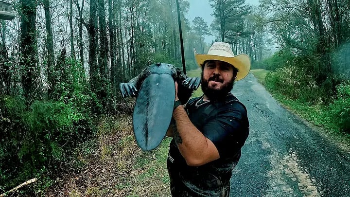 Person in cowboy hat holding large shield on misty forest road