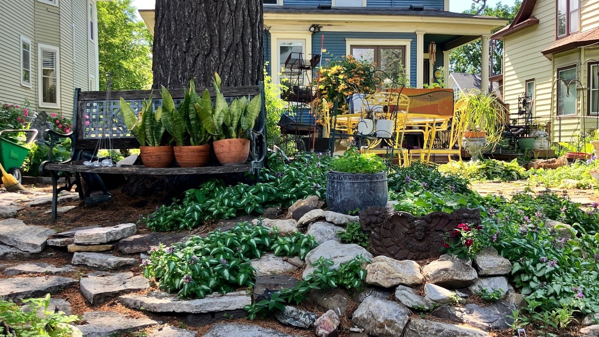 Charming garden with stone pathway, potted plants, and yellow outdoor furniture